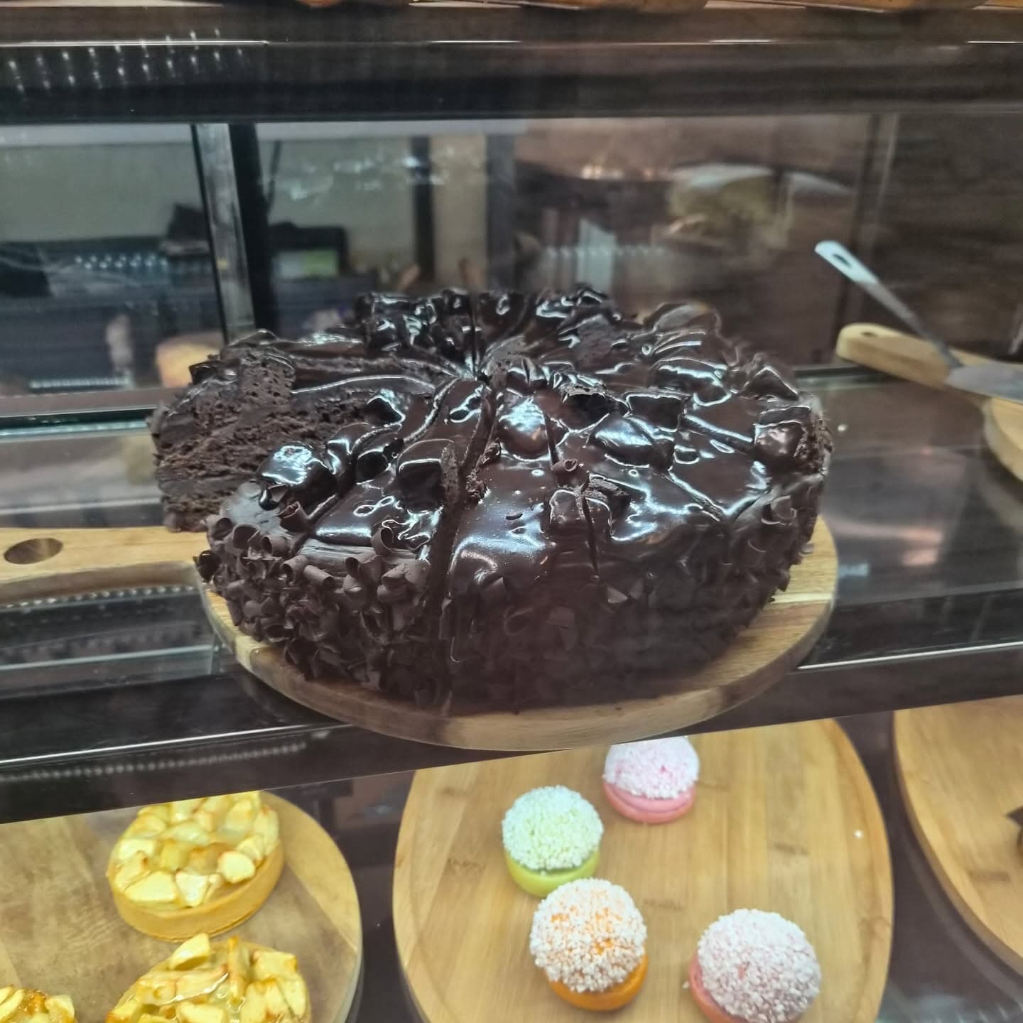 Un gâteau au chocolat glacé, entouré de copeaux, déjà tranché sur son plateau