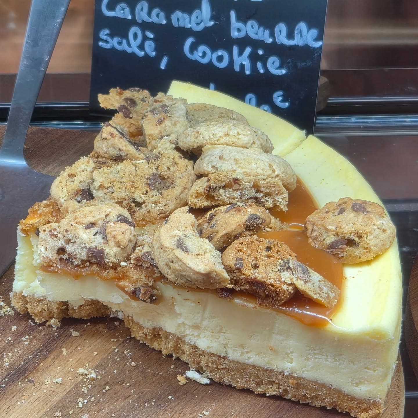 Une part de cheesecake au caramel beurre salé, couverte de morceaux de cookie