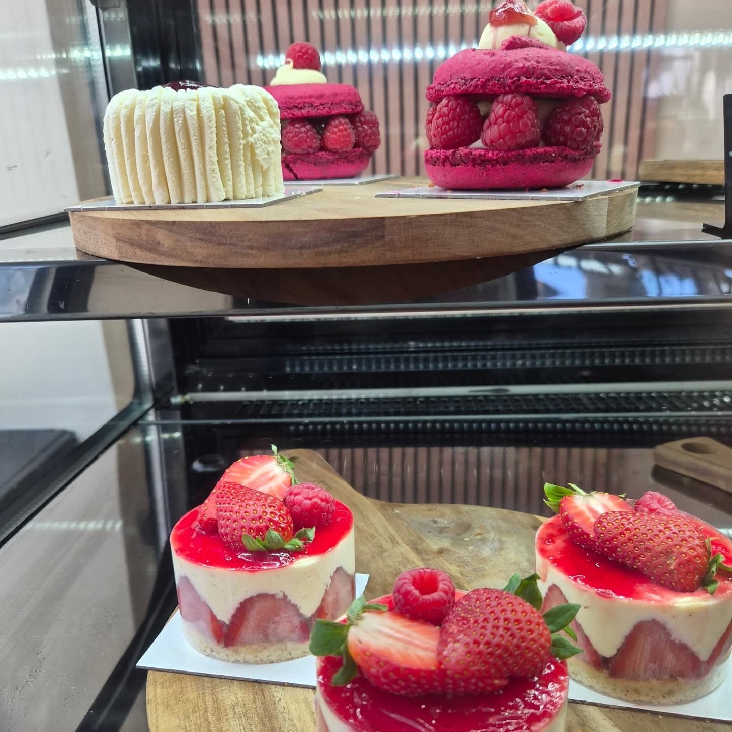Un macaron géant à la framboise et deux entremets à la fraise en vitrine
