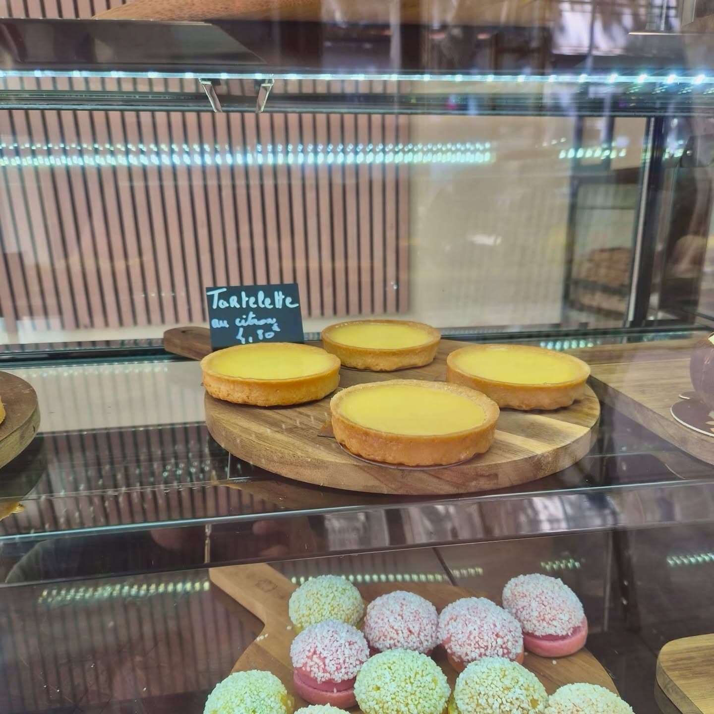 Quatre tartelettes au citron sur une planche ronde, ardoise manuscrite derrière