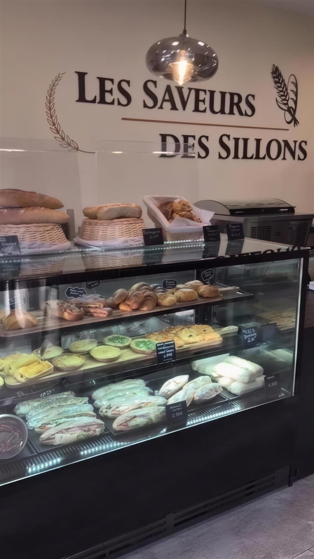 Le comptoir réfrigéré du midi sous l’enseigne peinte au mur, sandwichs et tartes salées